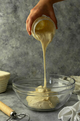 Wall Mural - Sourdough starter. Female hands pouring active sourdough over raw dough. Cooking rustic, homemade bread process,