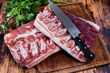 Wall Mural - fresh pork belly on a used cutting board resting on an old wooden table