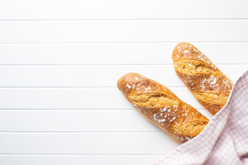 Two crispy fresh baguettes on white table.