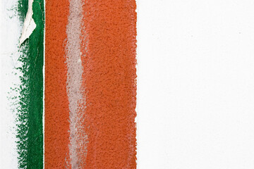 Detail of an old white cement wall with border of two painted vertical strips in green and orange color on the left side of frame. Abstract design with empty space for text and horizontal orientation