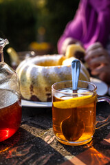 Wall Mural - Tea in cup with bundt cake on table. Serving dessert and hot drink outdoors