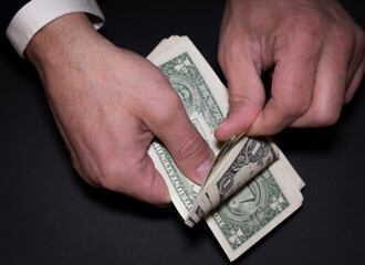 The businessman's hands count out a wad of dollars. Payment in cash.