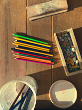 Top Above Overhead View Of A Table With A Set Of Coloring Pencils With A Variety Of Different Colors And A Chalk Box Full Of Small Colorful Chalk Pieces. Sunshine Casting A Shadow. Chalk Eraser On Top