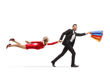 Poster - Man with shopping bags holding a flying woman in a red dress and running