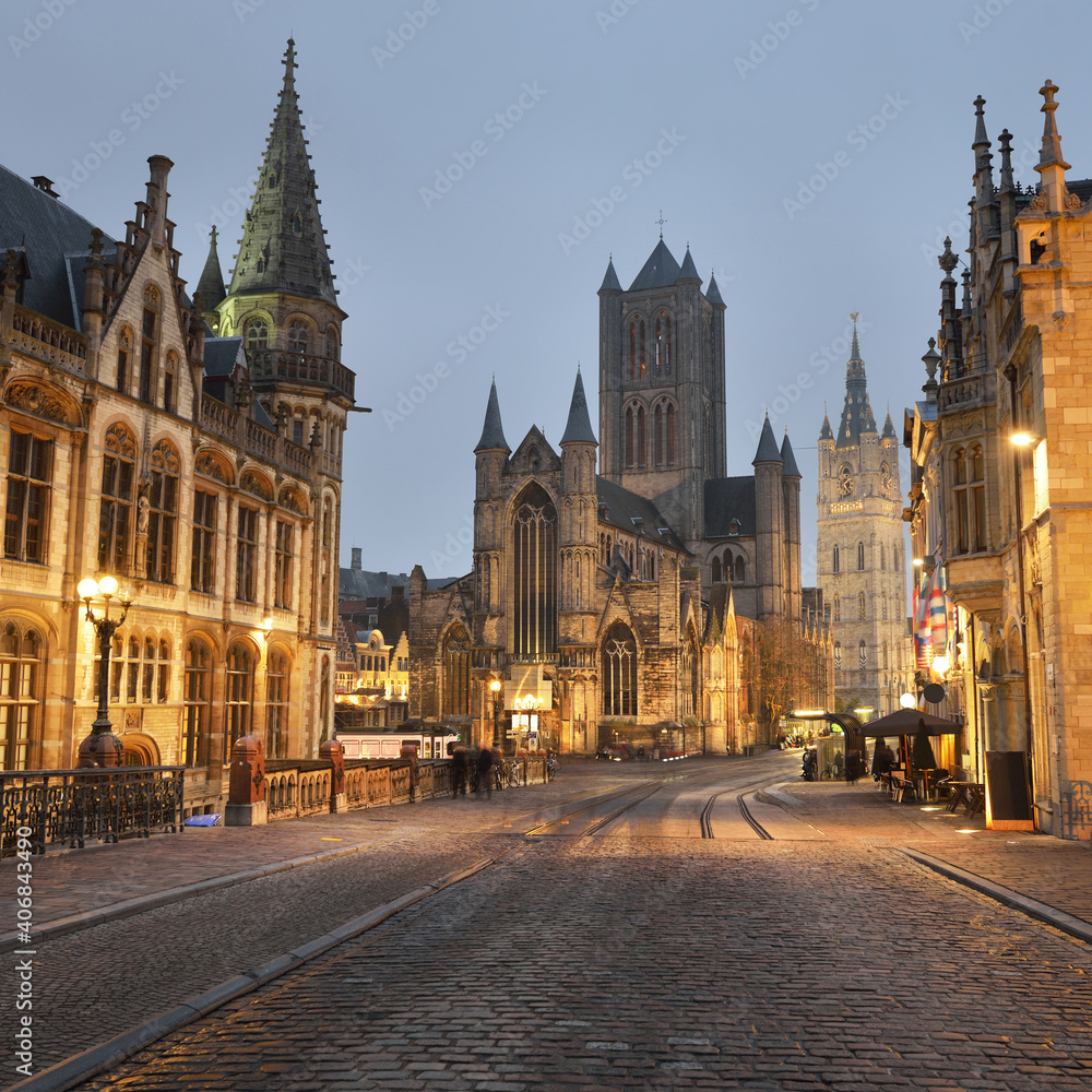 Illuminated street near St Michael bridge and St Bavo's Cathedral in a historical center of Ghent city. Night cityscape. Travel guide, national landmark, sightseeing theme. Belgium - obrazy, fototapety, plakaty 