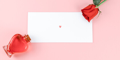 Wall Mural - 
Card with a rose and a heart.

Card with a rose and a heart lie diagonally on a pink background, close-up top view.