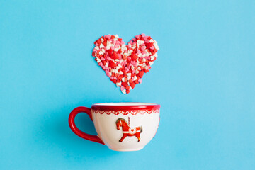 Wall Mural - Valentine's Day background February 14th. Heart made of red, pink, white hearts confetti and cup on bright blue background. Valentines day creative concept. Flat lay, top view, copy space