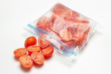 Packets of scattered frozen tomatoes on white plate with copy space