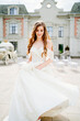 © andrey - cheerful beautiful woman in white wedding dress whirls near beautiful building.