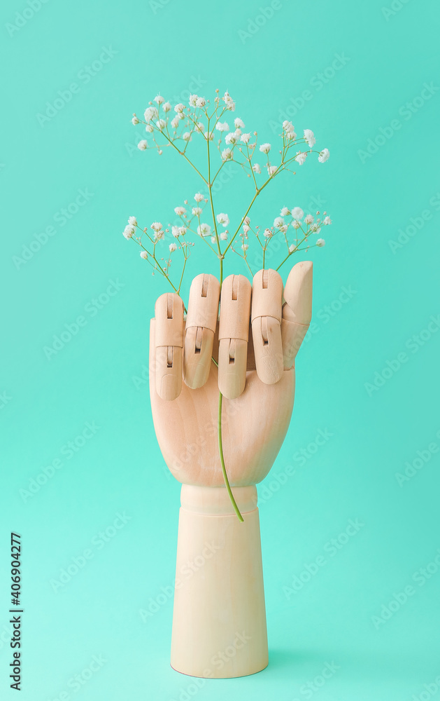 Wooden hand with flowers on color background
