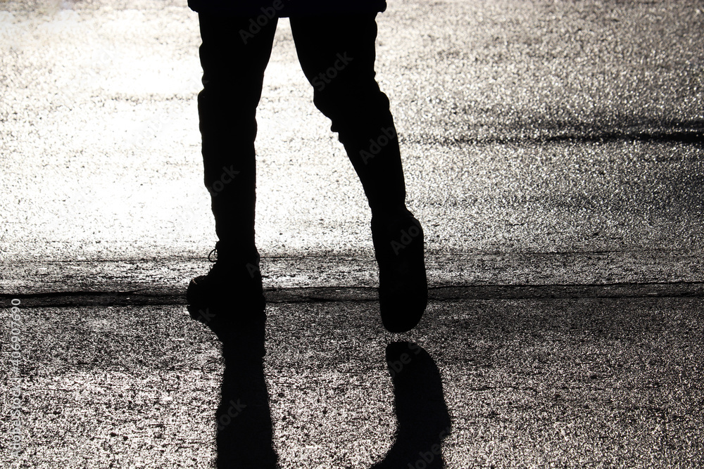 Black silhouette and shadow of person walking down on a street. Concept ...