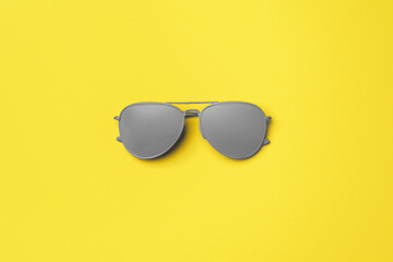 gray painted sunglasses on yellow background top view