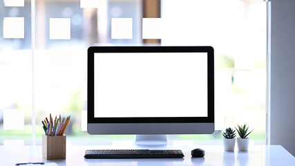 Wall Mural - Front view of modern computer, stationery and plant on white table. White empty screen for advertise text.