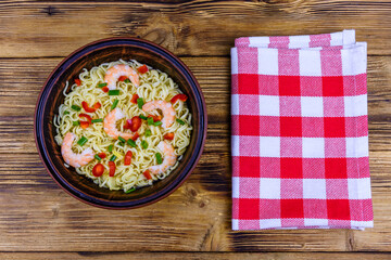 Instant noodle with shrimps, red pepper and green onion in a ceramic bowl. Japanese food. Top view