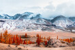 Snow-covered mountains with clouds and yellow trees. Autumn landscape of Kurai steppe in Altai, Siberia, Russia..