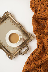Wall Mural - Lifestyle composition with cup of coffee with milk on vintage golden tray and knitted brown blanket plaid on white background. Breakfast in the morning. Flat lay, top view.