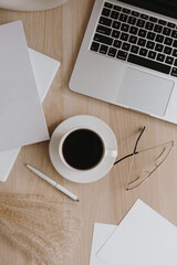 Wall Mural - Female home office desk workspace with coffee cup, laptop, glasses, pampas grass on wooden table. Flat lay, top view business, work at home concept. Lifestyle blog, social media composition.