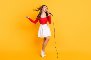 Sticker - Full length body size of female pop star singing song on stage keeping microphone isolated on vivid yellow color background