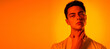 © master1305 - Thoughtful. Handsome caucasian man's portrait isolated on orange studio background in neon, monochrome. Beautiful male model. Concept of human emotions, facial expression, sales, ad, fashion beauty