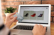 © New Africa - Woman with credit card using laptop for online shopping at table indoors, closeup