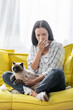 allergic woman with closed eyes holding paper napkin while sitting on couch with cat