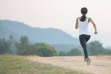 Wall Mural - Young lady enjoying in a healthy lifestyle while jogging along a country road, exercise and Fitness and workout on outdoors.