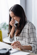young woman wiping nose with paper napkin while suffering from allergy on blurred foreground