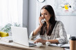 © LIGHTFIELD STUDIOS - allergic woman wiping nose with paper napkin while working at laptop on blurred foreground