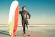 © Mangostar - Confident handicapped man standing on sea beach with board. Attractive brunette man with artificial leg wearing black wetsuit and looking at ocean. Physical disability and extreme sport concept