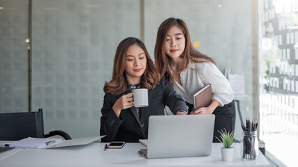 Wall Mural - Two asian businesswoman working laptop computer working and coffee at the office.