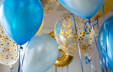 Blue and transparent balloons with golden confetti on the background of a large window. Light interior
