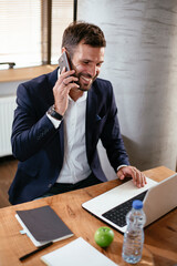 Smiling businessman talking to the phone. Young man using the phone in the office.