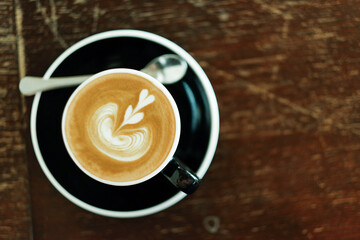 cappuccino in black ceramic cup  on wooden table