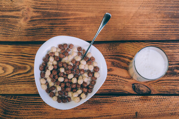 Cornflakes with a glass of milk on a wooden background.