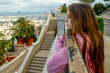 teenage girl in a lilac jacket against the background of the city of haifa, the Bahai Garden