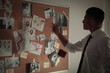 © New Africa - Detective looking at evidence board in office