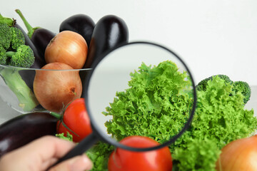 Wall Mural - woman with magnifying glass exploring vegetables, closeup. poison detection