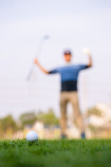 Green grass with golf ball close-up in soft focus at sunlight and have blur background with man playing golf end game successful.