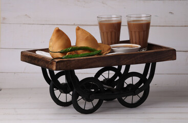 Indian snack Homemade spicy and delicious samosa served with green, tamarind chutney cutting masala tea, chai, 