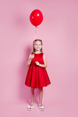 Wall Mural - Valentines day. Little girl in red dress with heart shape air balloon on pink background