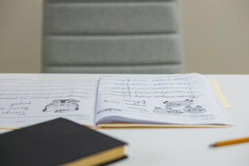 boy in blue sweater doing homework at the table at home