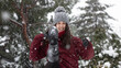 © arturo - Photoshoot with a model in the snow, she wears a red coat and a gray hat. He's kicking the snow. It's snowing.