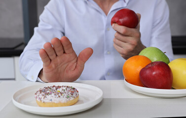 Man refuses to eat junk food sweets and choose fruits for dessert. Healthy eating and active lifestyle concept