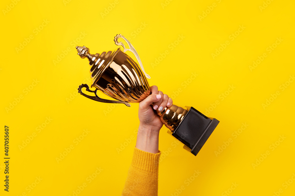Hand of the person with a sports cup over yellow background - obrazy, fototapety, plakaty 