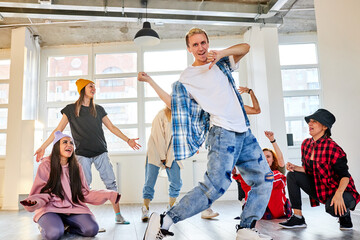 male dancer practicing brakedance moves, performing modern dance element, group of dancers next to him