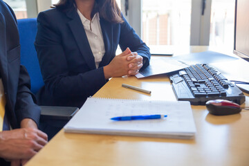 Wall Mural - Cropped shot of business people during meeting, Partners sitting at workplace and talking. Office employees desk with notebooks, pens, pc keyboard. Closeup Business meeting concept