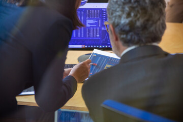 Wall Mural - Finance professionals watching trading dynamics on monitors and document, analyzing stock market statistics. Finance or investment concept