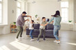 © Studio Romantic - Happy young family with kids enjoying free time on weekend at home. Parents and children dancing and having fun in spacious living-room, celebrating moving into new house or rented apartment