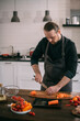 © Anna - A male cook prepares vegetables at home in the kitchen