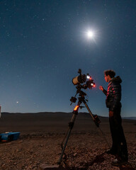 one astronomer man looking the night sky through an amateur telescope and taking photos to the chris
